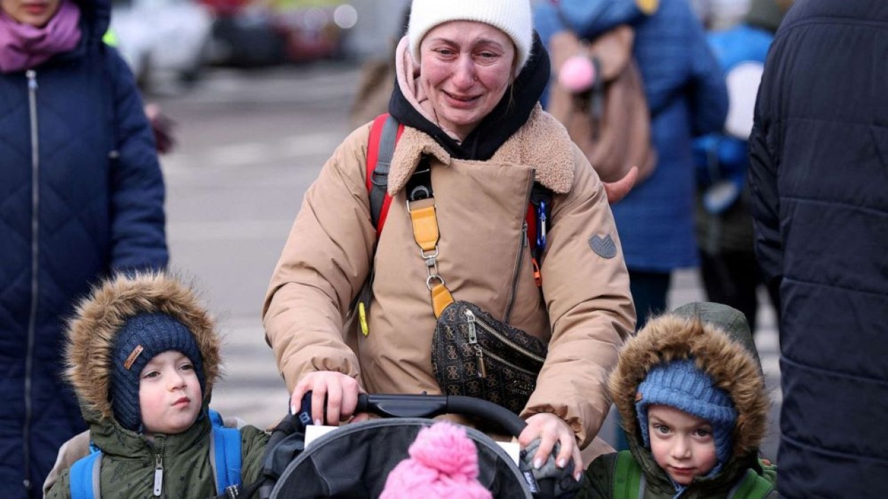Seorang wanita menangis saat dia berjalan dengan anak-anaknya setelah melarikan diri dari invasi Rusia ke Ukraina. (Stoyan Nenov/Reuters)