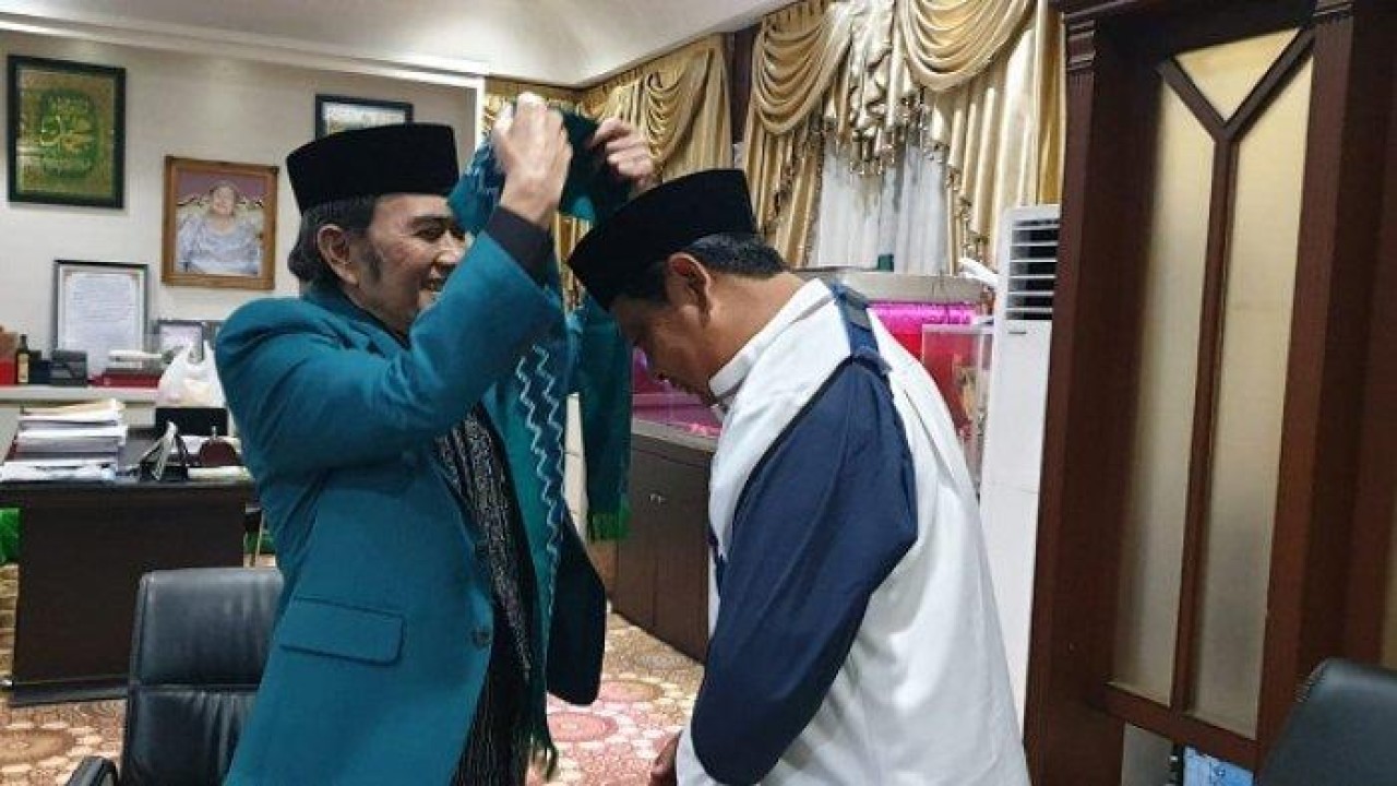 Rhoma Irama (kiri) menyematkan syal kehormatan kepada Gubernur Kalsel Sahbirin Noor. Foto:  Biro Adpim Setdaprov Kalsel