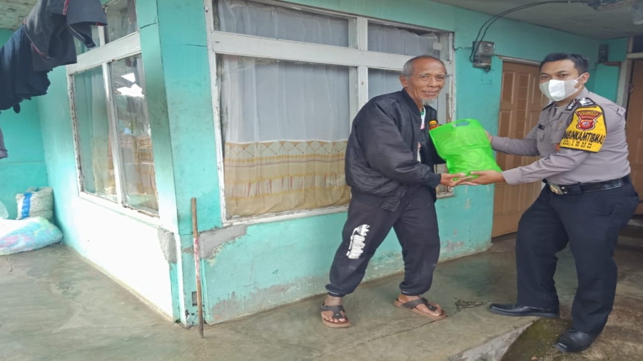 Petugas kepolisian membagikan sembako kepada warga