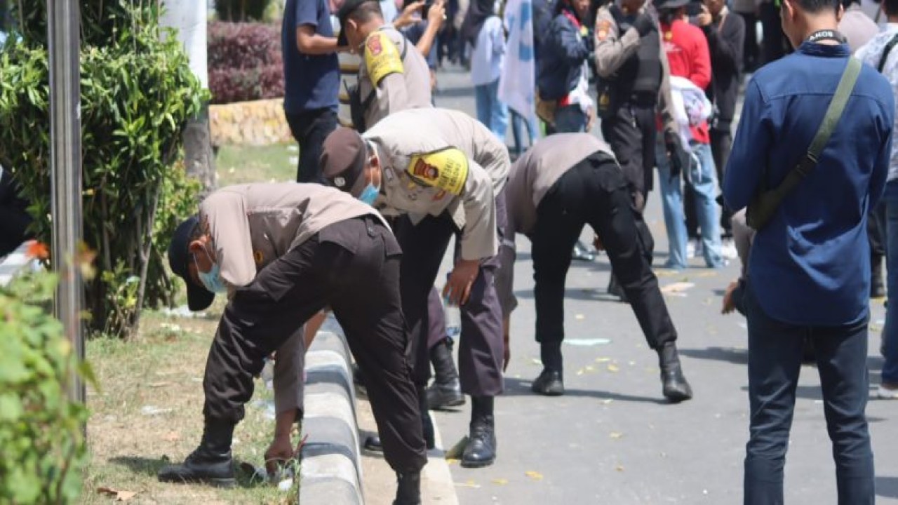 Sejumlah personil Polresta Mataram sedang memungut sampah di sela-sela mengamankan aksi demo kenaikan harga BBM di Kantor DPRD Provinsi NTB. Foto (Istimewa)