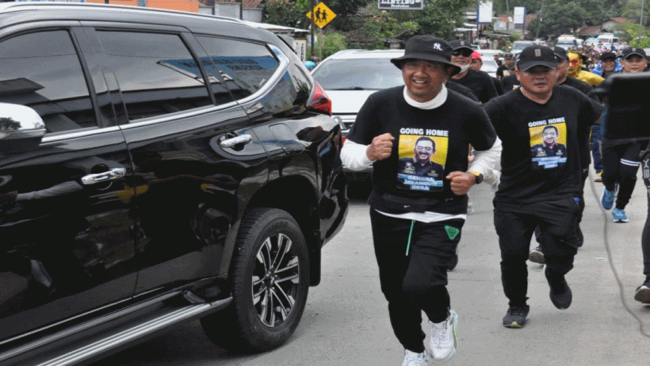 Bupati Cilacap Tatto Suwarto Pamuji (depan) berlari kecil dalam perjalanan memenuhi nazar berjalan kaki dari rumah dinas menuju kediaman pribadi di Desa Ciguling, Kecamatan Majenang, Cilacap, Senin (14-11-2022), menjelang berakhirnya masa jabatannya sebagai kepala daerah setempat. ANTARA/HO-Dinkominfo Cilacap