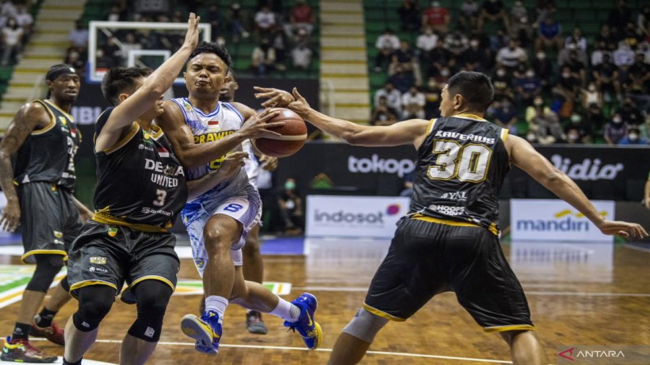 Arsip - Pebasket Dewa United Surabaya Xaverius Prawiro (kanan) dan Nikholas Mahesa R (kiri) berusaha menghadang gerak pebasket Prawira Bandung Yudha Saputera (kedua kanan) saat pertandingan Playoff Liga Bola Basket Indonesia (IBL) Tokopedia 2022 di Gor C-Tra Arena, Bandung, Jawa Barat, Selasa (16/8/2022). . ANTARA FOTO/M Agung Rajasa/foc.