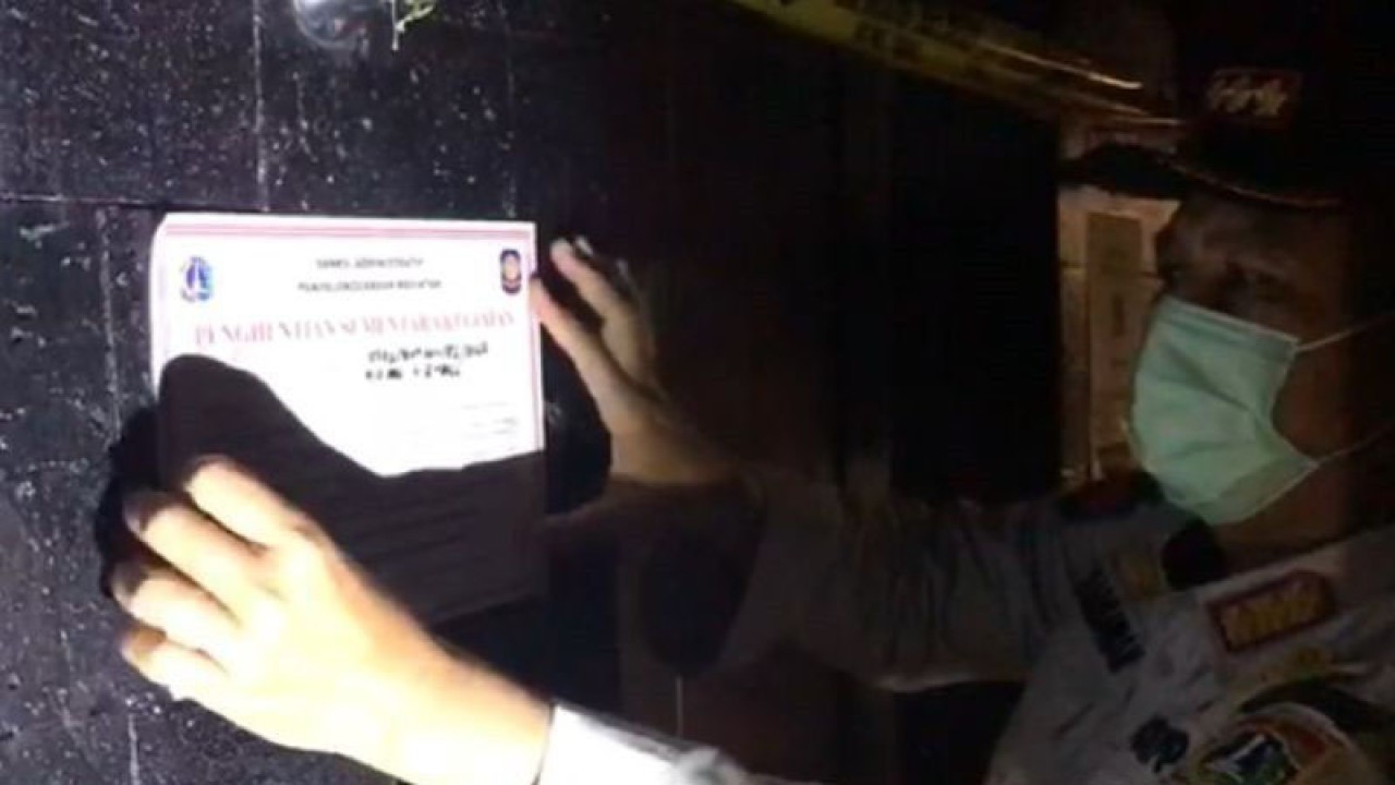 Kepala Satuan Polisi Pamong Praja Jakarta Selatan Ujang Harmawan menempelkan tanda penutupan sementara di salah satu bar di kawasan Senopati, Kebayoran Baru, Jakarta Selatan, Jumat, (4/2/2022). ANTARA/HO-Pokja Jakarta Selatan/am.