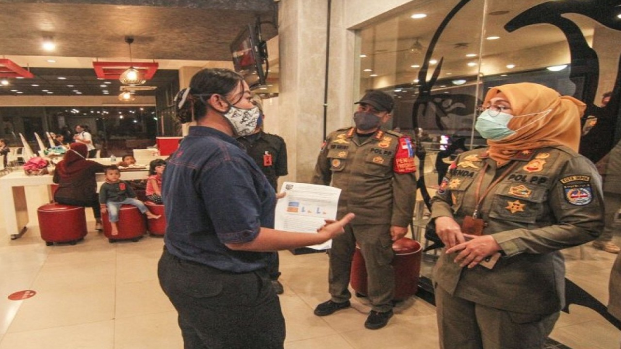 Petugas Satpol pp memberikan sosialisasi pembatasan jam malam kepada pedagang di kawasan Margonda, Depok, Jawa Barat, Senin (31/8/2020). Pemkot Depok menerapkan pembatasan jam malam yakni batas operasional pukul 18.00 WIB untuk pertokoan, pukul 20.00 WIB untuk aktivitas warga, dan pukul 21.00 WIB untuk kurir barang, terkait meningkatnya angka kasus positif dalam dua minggu terakhir. ANTARA FOTO/Asprilla Dwi Adha/aww.