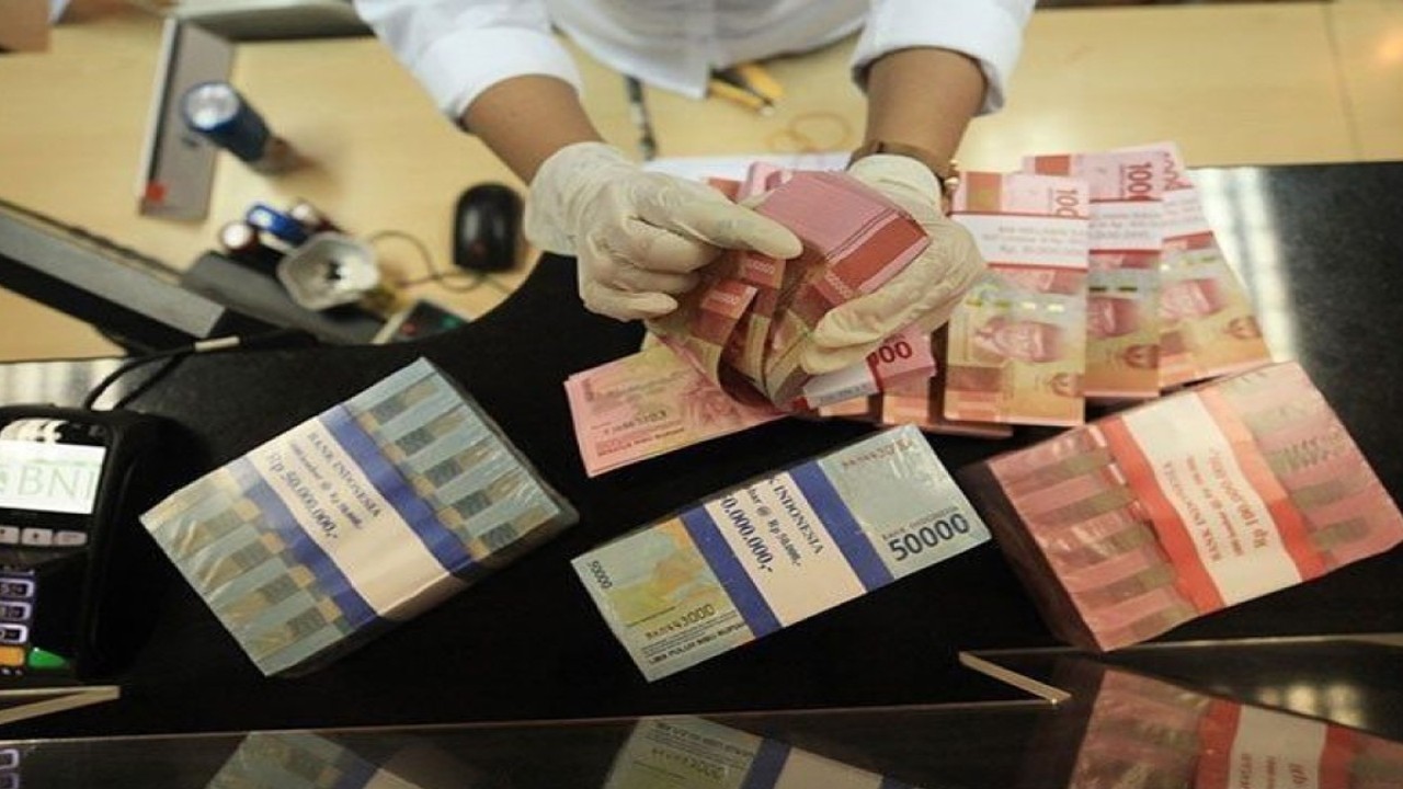 Petugas menghitung uang rupiah dan dolar AS