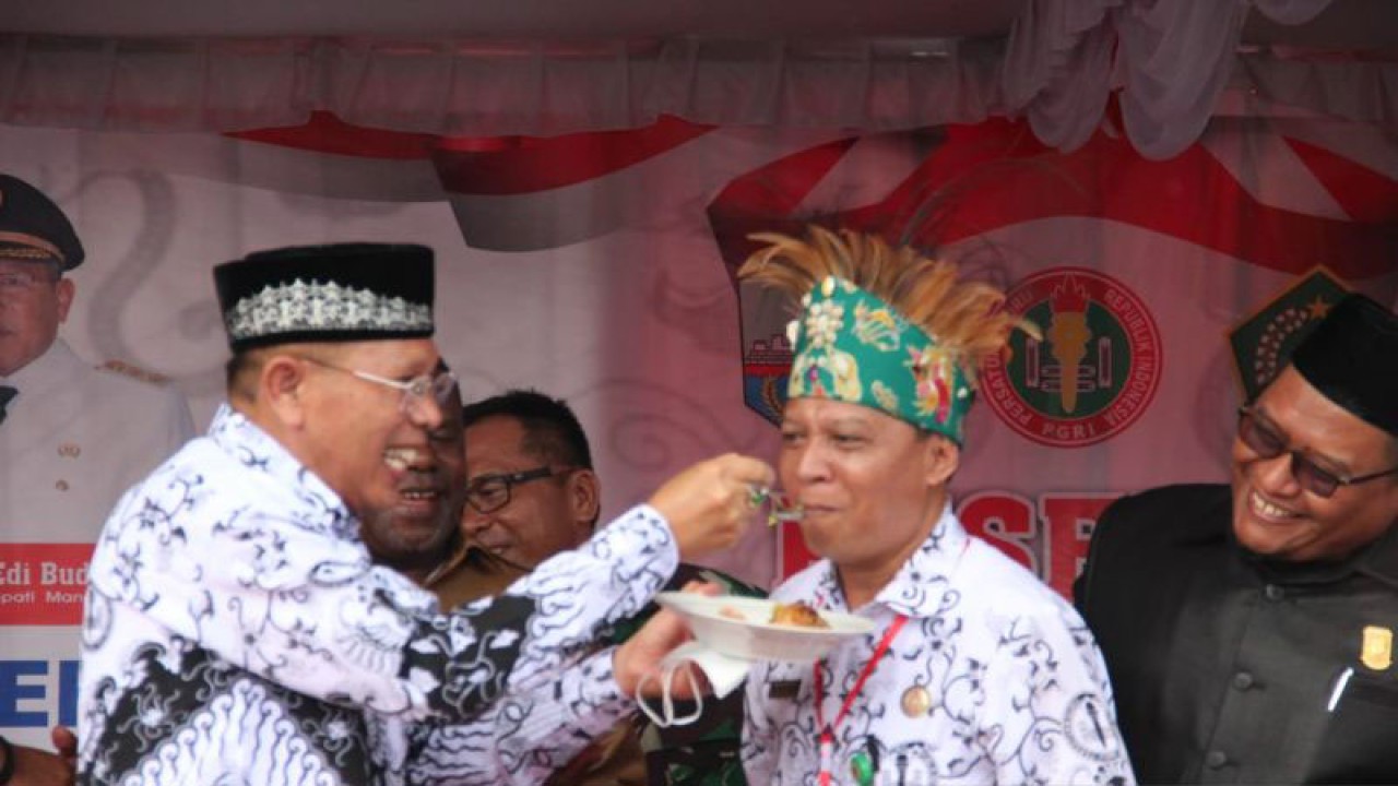 Wakil Bupati Manokwari, Edi Budoyo menyuapi nasi tumpeng kepada Ketua PGRI Manokwari, Naharuddin dalam peringatan puncak HUT ke-77 PGRI dan Hari Guru Nasional di Lapangan Borasi Manokwari, Selasa (29/11/2022). ANTARA/Rachmat Julaini