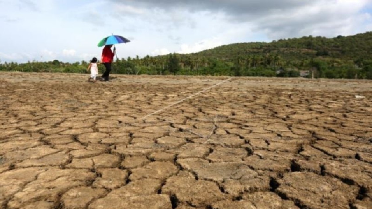 Arsip - Warga melintas di dekat tambak yang kering akibat musim kemarau di kawasan Ladong, Aceh Besar, Aceh, Selasa (9/7/2019). (ANTARA FOTO/Irwansyah Putra)