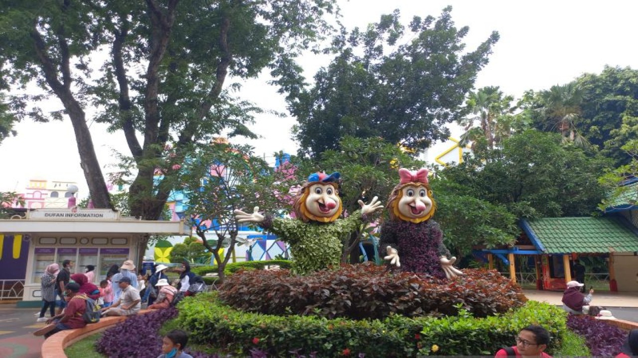 Sejumlah pengunjung tampak beristirahat di dekat dua buah patung maskot Dufan dari jenis kera Bekantan di kawasan unit rekreasi Dunia Fantasi, Taman Impian Jaya Ancol, Pademangan, Jakarta Utara, Kamis (22/12/2022). ANTARA/HO-Wisata Kreatif Jakarta