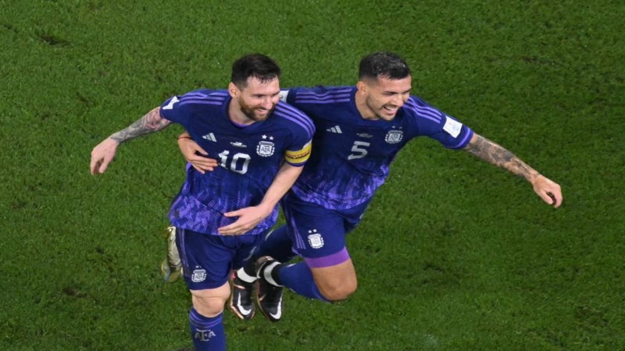 Penyerang dan gelandang Argentina Lionel Messi (kiri) dan Leandro Paredes merayakan kemenangan mereka atas Polandia seusai pertandingan terakhir Grup C Piala Dunia 2022 di Stadium 974, Doha, Rabu (30/11/2022). Argentina menang 2-0 atas Polandia. (AFP/ANTONIN THUILLIER)