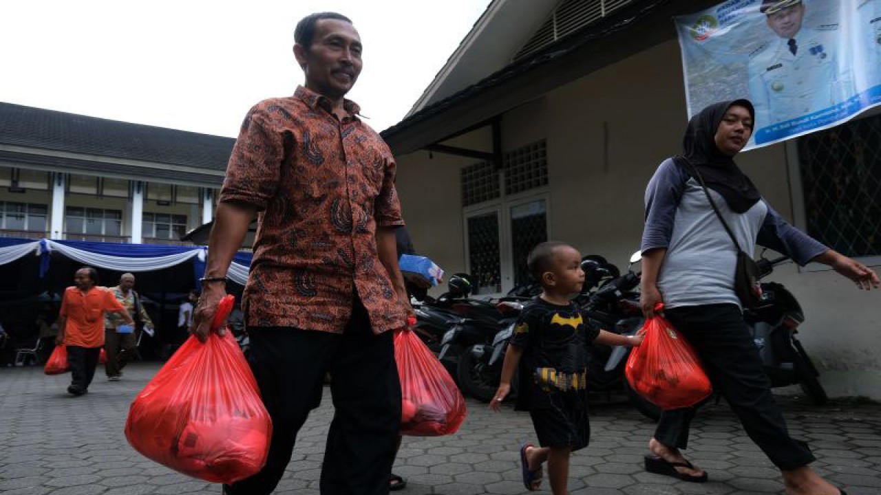 Sejumlah warga membawa paket sembako usai menerima pembagian penyaluran bahan pangan Data Terpadu Kesejahteraan Sosial (DTKS) Non Bansos di Kantor Kecamatan Pontianak Kota, Kalimantan Barat, Rabu (14/12/2022). Pemerintah Kota Pontianak menyalurkan 17.459 paket sembako kepada masyarakat yang terdampak inflasi di lima kecamatan di wilayah setempat dalam rangka pengendalian inflasi. ANTARA FOTO/Jessica Helena Wuysang/wsj (ANTARA FOTO/JESSICA HELENA WUYSANG)