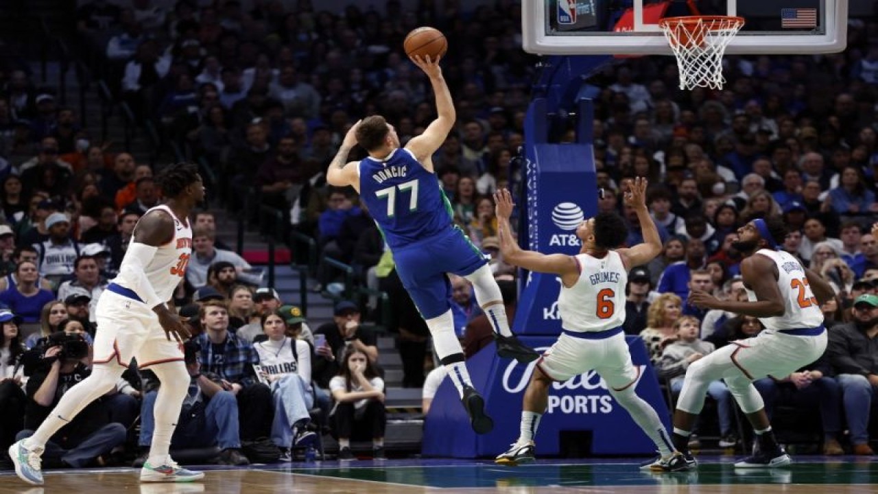 Pemain Dallas Mavericks Luka Doncic memasukkan bola di tengah hadangan pemain New York Knicks Quentin Grimes di American Airlines Center, Dallas, Texas, 27 Desember  2022. (Photo by Tim Heitman / GETTY IMAGES NORTH AMERICA / Getty Images via AFP) (Getty Images via AFP/TIM HEITMAN)