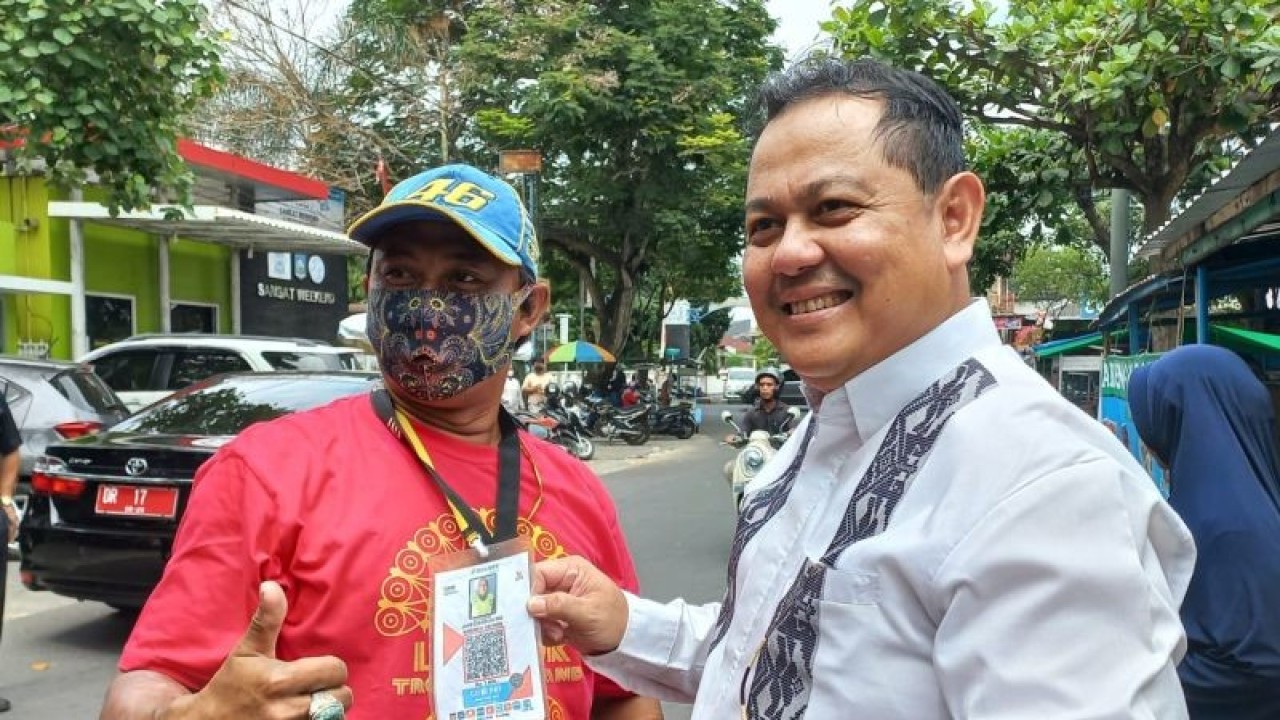 Kepala Perwakilan Bank Indonesia Provinsi NTB Heru Saptaji (kanan), menunjukkan barcode Quick Response Code Indonesian Standard (QRIS) yang dipakai tukang parkir untuk melayani pembayaran jasa parkir secara non-tunai. (ANTARA/Awaludin)