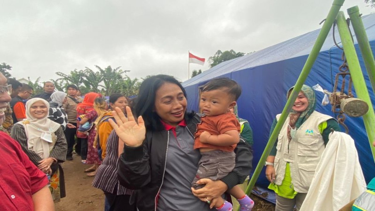 Menteri PPPA Bintang Puspayoga saat menggendong seorang anak korban gempa bumi Cianjur, Jawa Barat sembari meninjau posyandu darurat pada Kamis (29/12/2022). (ANTARA/Hreeloita Dharma Shanti)