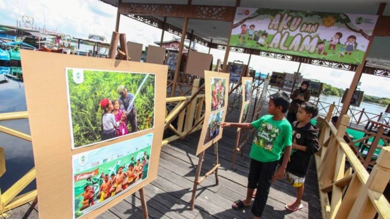 Sejumlah anak mengamati karya yang dipamerkan pada pameran foto bertajuk Festival Anak Sebangau Aku dan Alam di wisata Kereng Bangkirai, Palangka Raya, Kalimantan Tengah, Minggu (11/12/2022). Pameran yang digelar Borneo Nature Foundation (BNF) tersebut menampilkan karya gambar anak-anak di wisata itu dan 57 karya foto dokumentasi selama kegiatan mengedukasi pelestarian alam bersama Anak Sebangau serta Sebangau Ranger yang telah dibina oleh BNF selama tujuh tahun. (ANTARA FOTO/Makna Zaezar/nym.)
