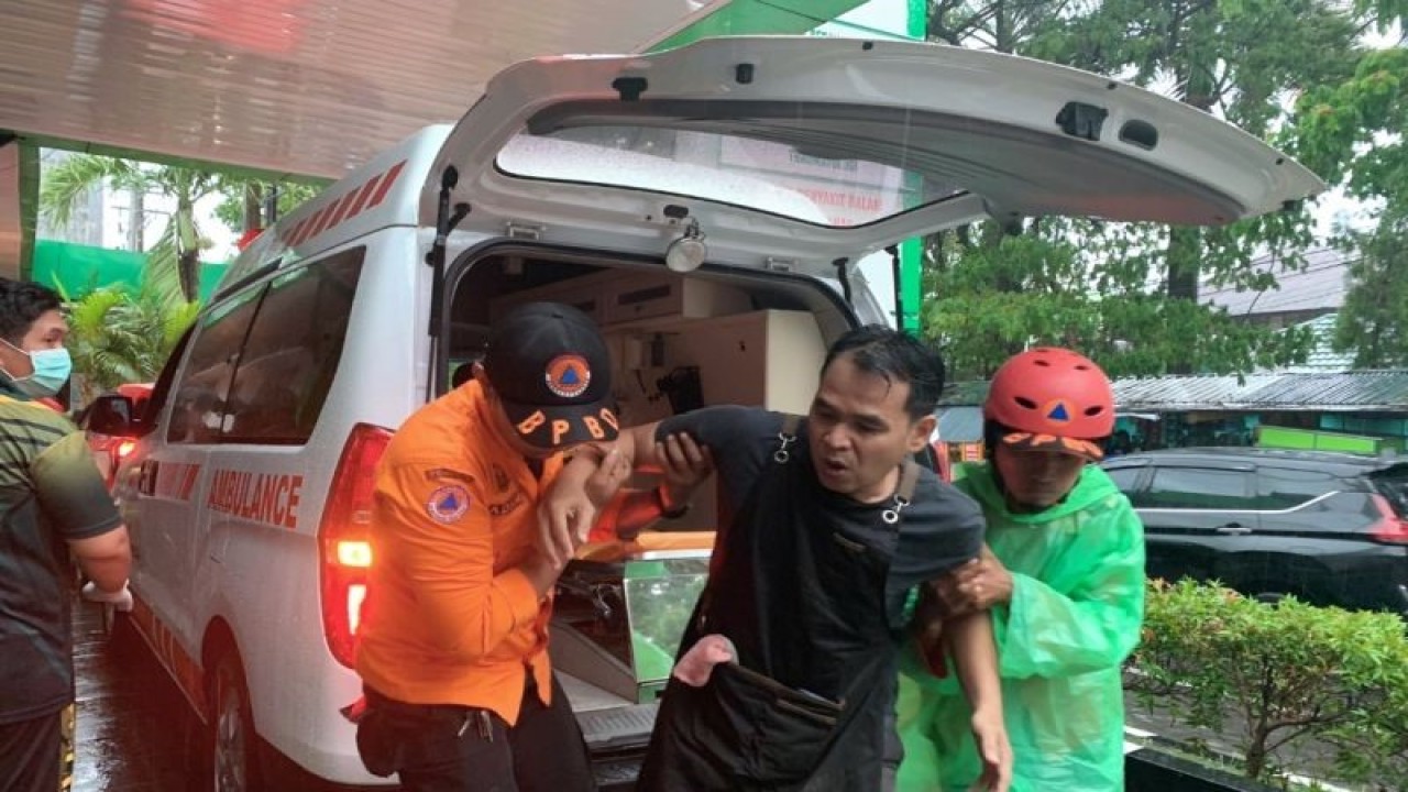 Petugas BPBD dan personel pemadam kebakaran membantu warga yang tertimpa batang pohon tumbang ke Rumah Sakit Pelamonia di Kota Makassar, Provinsi Sulawesi Selatan, Jumat (23/12/2022). (ANTARA/HO Humas BPBD Makassar)