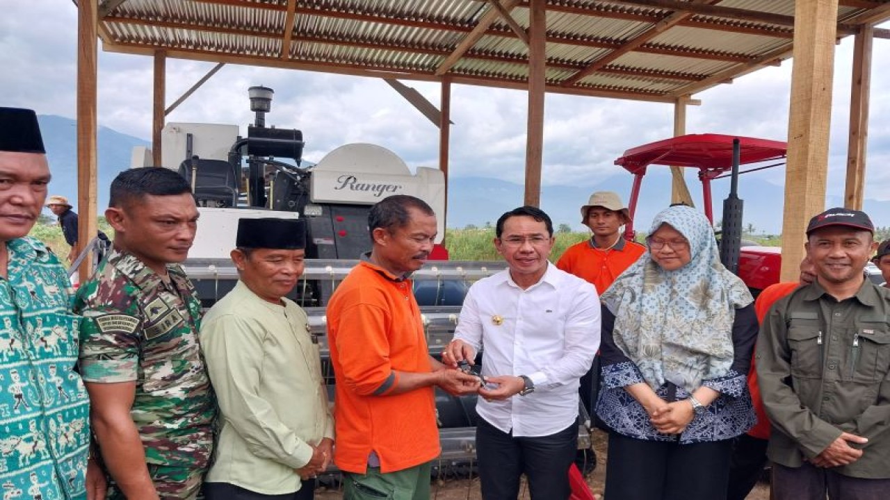 Bupati Sigi Mohamad Irwan (kemeja putih) menyerahkan secara simbolis kunci alat mesin pertanian jenis combine harvester kepada pengurus Kelompok Tani Makmur Perkasa, di Desa Karawana, Kecamatan Sigi Biromaru, Jumat (30/12/2022). (ANTARA/Muhammad Hajiji)