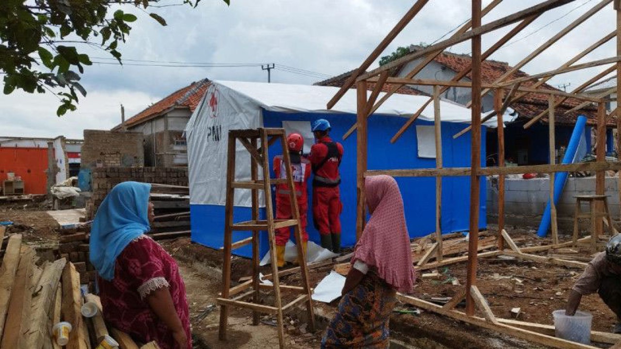 Warga Kampung Rawacina, Desa Nagrak, Kabupaten Cianjur, Jawa Barat, memperhatikan relawan PMI yang sedang membangun hunian darurat yang segera mereka tempati di bekas reruntuhan rumahnya, Kamis (22/12/2022). ANTARA/Ahmad Fikri