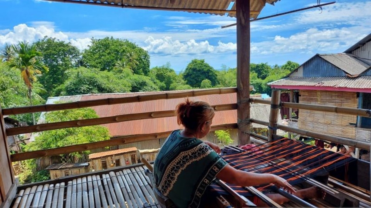 Salah seorang warga Desa Pajam sedang menenun di teras rumah panggung di Desa Pajam Kecamatan Kaledupa Selatan Kabupaten Wakatobi, Sulawesi Tenggara. (ANTARA/Aditya Ramadhan)