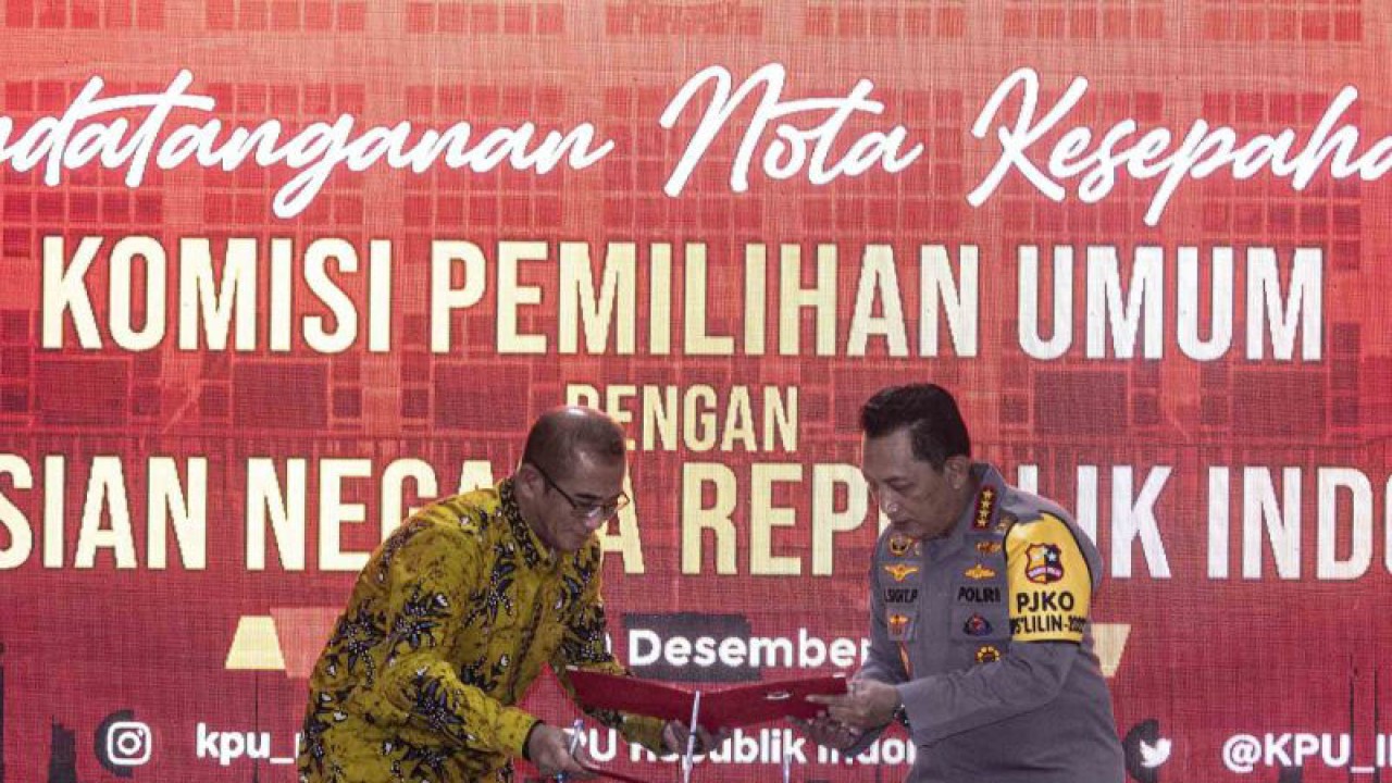 Ketua Komisi Pemilihan Umum (KPU) Hasyim Asy'ari (kiri) bersama Kapolri Jenderal Pol Listyo Sigit Prabowo (kanan) bertukar dokumen dalam penandatanganan nota kesepahaman antara KPU dengan Polri di Gedung KPU, Jakarta, Kamis (29/12/22). Penandatanganan nota kesepahaman tersebut sinergitas pelaksanaan tugas dan fungsi dalam penyelenggaraan pemilihan umum dan pemilihan serentak tahun 2024. ANTARA FOTO/Aprillio Akbar/wsj.