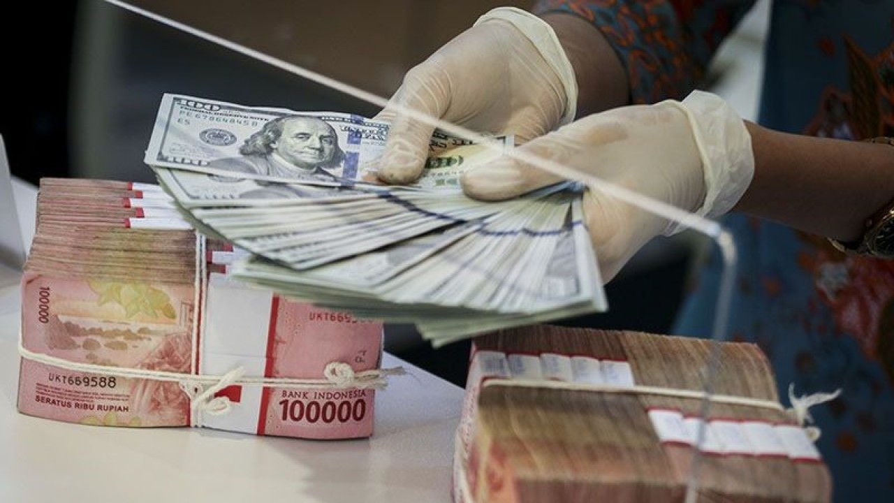 Ilustrasi: Petugas bank sedang menghitung uang dolar AS di bawah tumpukan rupiah di Jakarta. ANTARA FOTO/Rivan Awal Lingga/tom.