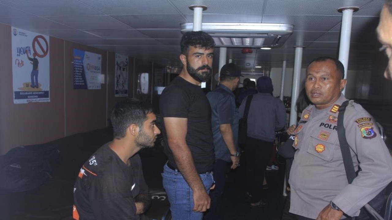 Dok. Aparat Kepolisian Resor Rote Ndao mengawal WNA asal Irak yang baru tiba di dermaga penyeberangan Bolok Kupang, NTT, Sabtu (17/12/2022). ANTARA FOTO/Kornelis Kaha.