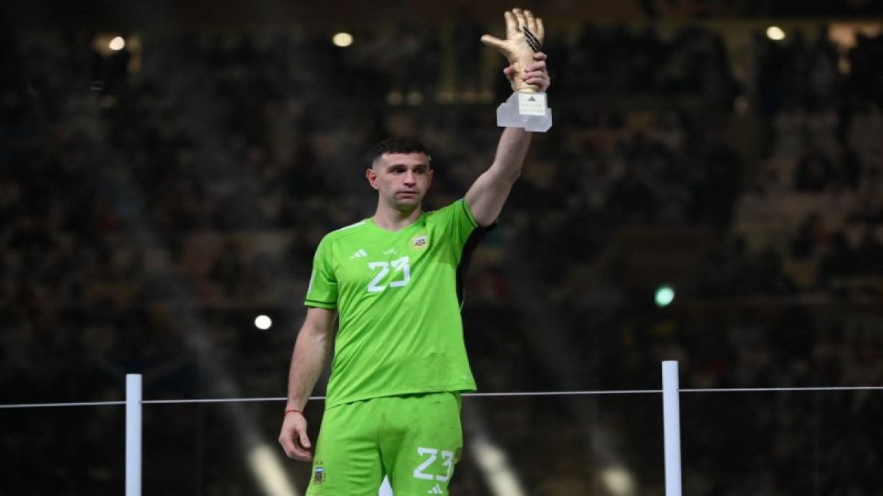 Penjaga gawang Argentina Emiliano Martinez mengangkat Golden Glove setelah dinobatkan sebagai kiper terbaik Piala Dunia 2022 usai final antara Argentina dan Prancis di Stadion Lusail, Lusail, Doha, 16 Desember 2022. (Photo by FRANCK FIFE / AFP) (AFP/FRANCK FIFE)