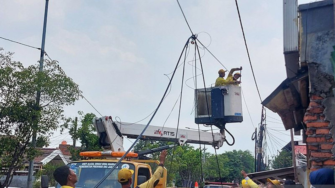 Petugas Dinas Bina Marga DKI Jakarta melakukan pemotongan kabel udara di Jalan Jatinegara Kaum, Jakarta, Kamis (1/12/2022). ANTARA/Yogi Rachman/am.