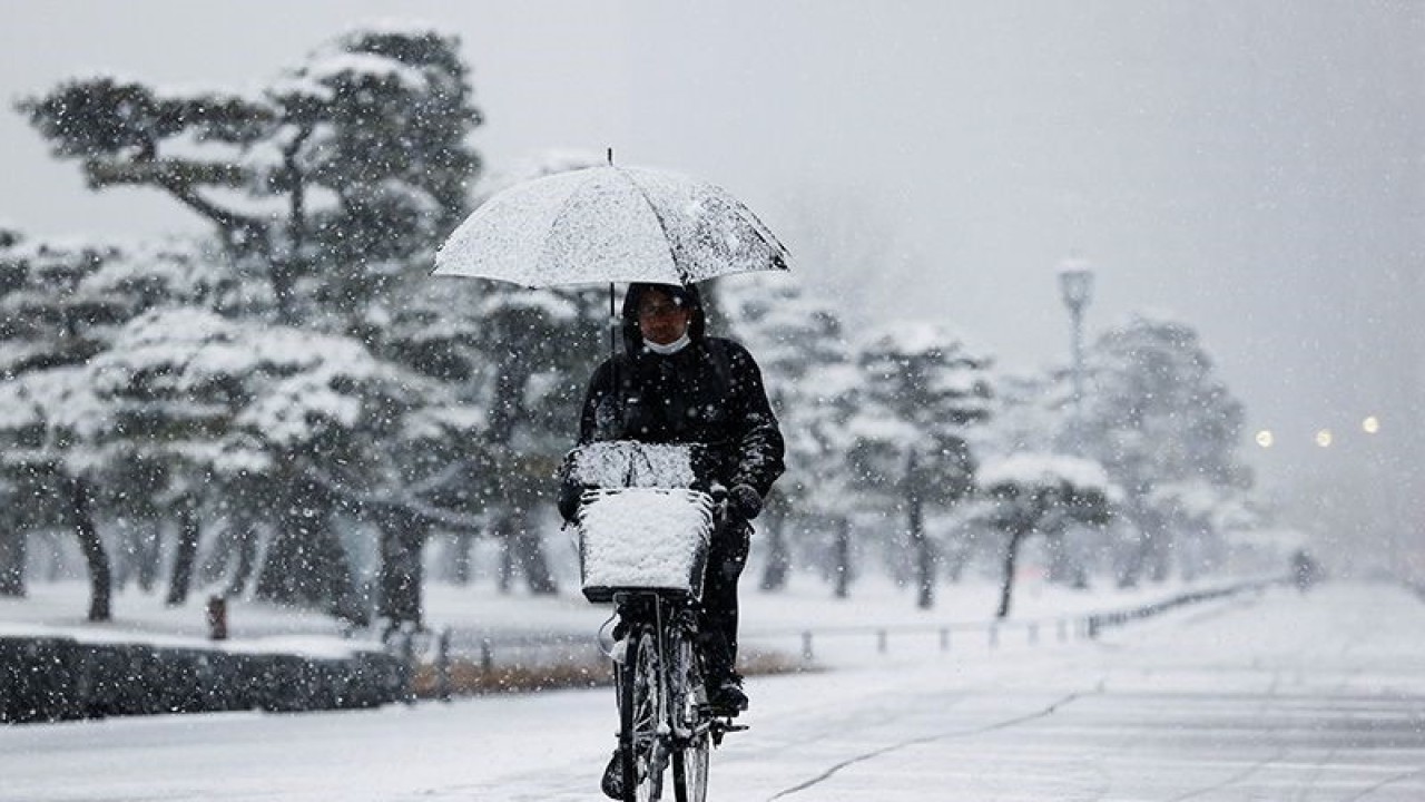 Arsip - Seorang pria mengendarai sepeda di tengah hujan salju saat pandemi COVID-19, di Tokyo, Jepang, 6 Januari 2022. (ANTARA FOTO/REUTERS/Issei Kato/aww)