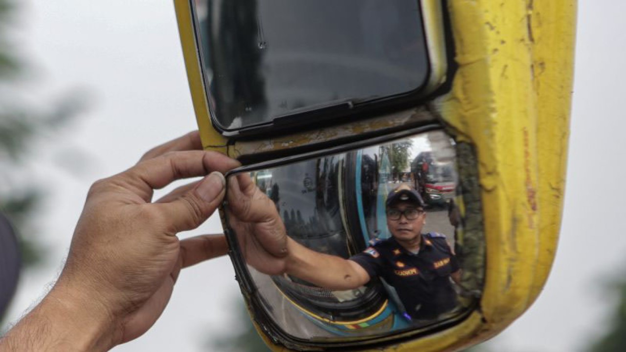 Petugas memeriksa kondisi kaca spion bus saat melakukan pemeriksaan kelaikan kendaraan (ramp check) di Terminal Kalideres, Jakarta, Senin (19/12/2022). ANTARA FOTO/Fauzan/aww.