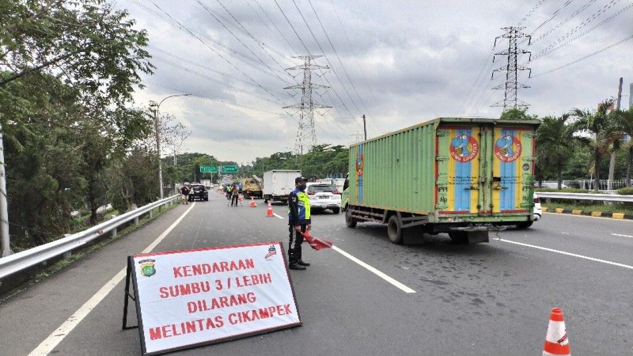 Petugas melakukan pengaturan lalu lintas dekat papan pengumuman bertuliskan kendaraan sumbu tiga atau lebih dilarang melintas Cikampek di Interchange Cawang, Jakarta, Jumat (23/12/2022). ANTARA/Aji Cakti