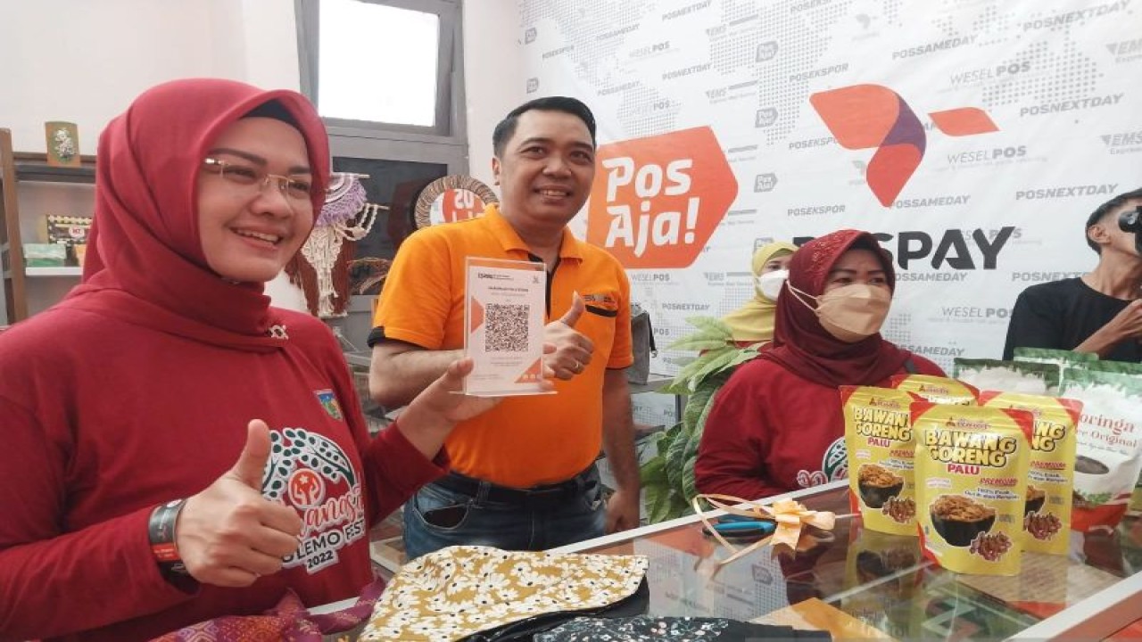 Ketua Dekranasda Kota Palu Diah Puspita (kiri) didampingi EGM PT Pos Indonesia KCU Palu Subhan (kanan) memperlihatkan aplikasi QRIS dalam meninjau galeri UMKM, di Kantor PT Pos KCU Palu, Minggu (11/12/2022). (ANTARA/Muhammad Hajiji)