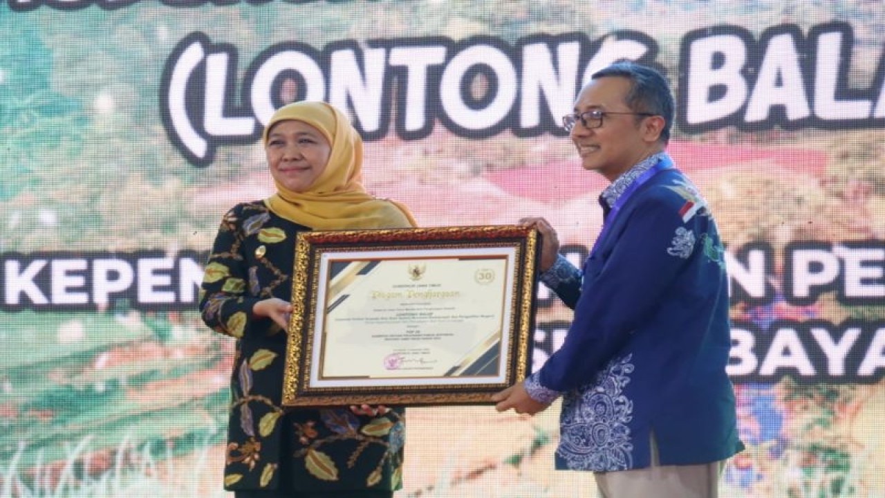 Gubernur Jawa Timur Khofifah Indar Parawansa menyerahkan penghargaan Kovablik Jatim 2022 kepada Kepala Dispendukcapil Surabaya Agus Sonhaji di Alun-Alun Kireksogati Caruban, Kecamatan Mejayan, Kabupaten Madiun, Rabu (7/12/2022). (ANTARA/HO-Diskominfo Surabaya)