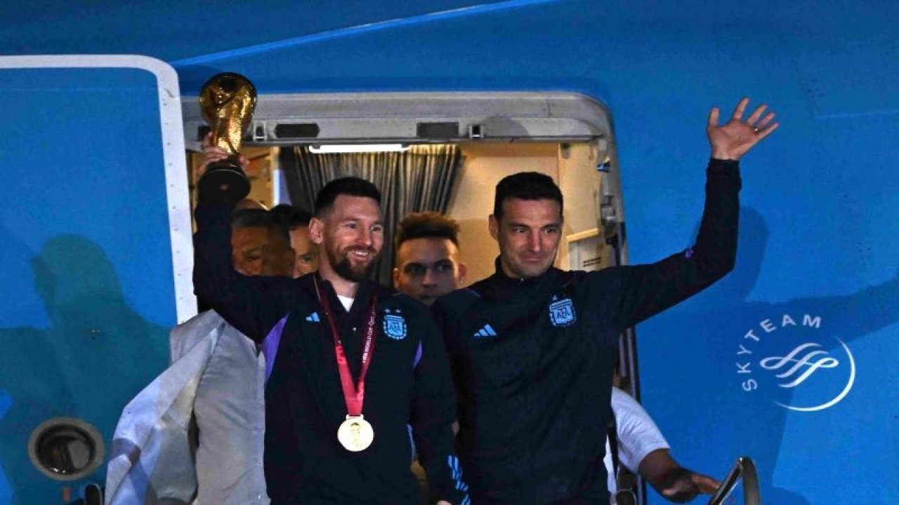 Kapten timnas Argentina Lionel Messi (kiri) memegang trofi Piala Dunia bersama pelatih Lionel Scaloni saat mereka tiba di Bandara Internasional Ezeiza, Buenos Aires pada 20 Desember 2022. ANTARA/AFP/LUIS ROBAYO