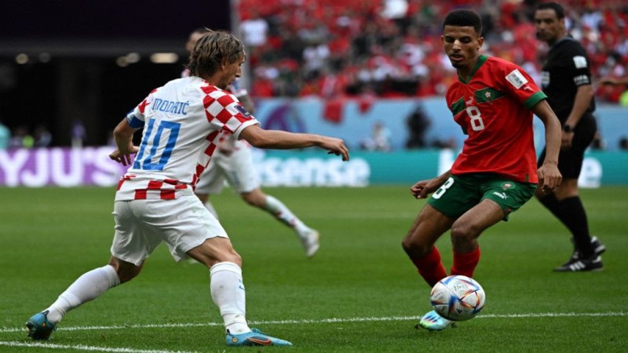 Gelandang Kroasia Luka Modric berduel dengan gelandang Maroko Azzedine Ounahi dalam pertandingan Grup F Piala Dunia 2022 antara Maroko dan Kroasia di Stadion Al-Bayt, Doha, pada 23 November 2022. Kedua gelandang kembali berhadapan dalam laga perebutan tempat ketiga Sabtu 17 Desember ini. (Photo by OZAN KOSE / AFP) (AFP/OZAN KOSE)