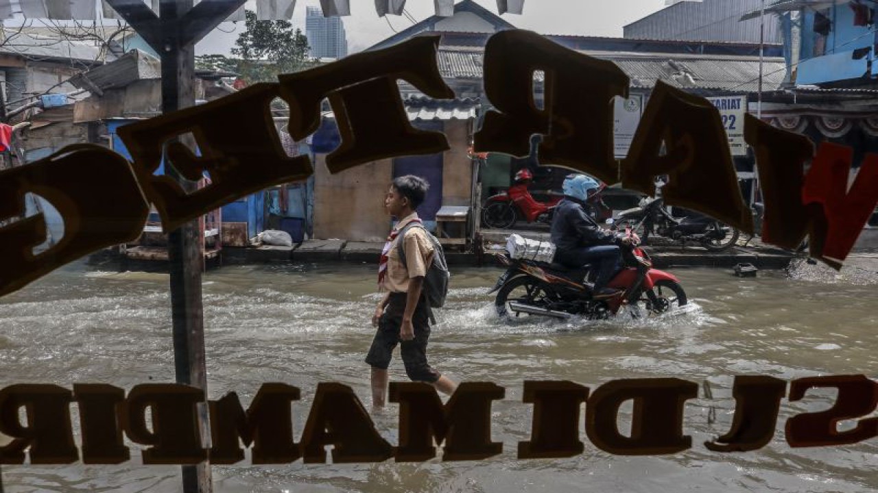 Siswa tengah melintas banjir rob di Muara Angke, Jakarta, Rabu (7/12/2022). BMKG merilis sembilan wilayah pesisir DKI Jakarta berpotensi terdampak banjir rob akibat adanya aktivitas pasang air laut yang diperkirakan terjadi pada 6 - 13 Desember 2022. ANTARA FOTO/Darryl Ramadhan/aww.
