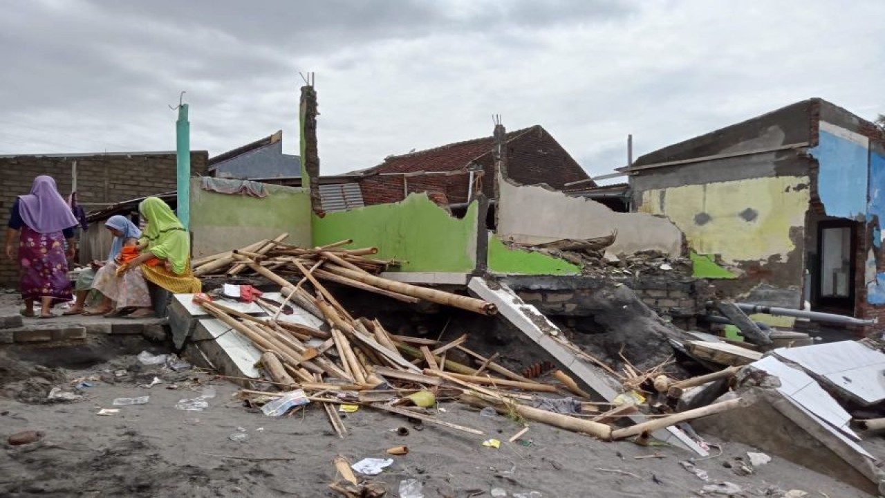 Sejumlah ibu-ibu duduk di samping runtuhan rumah yang terdampak abrasi di Lingkungan Mapak Indah Kota Mataram, Provinsi Nusa Tenggara Barat, Senin (26/12-2022). (Foto: ANTARA/Nirkomala)