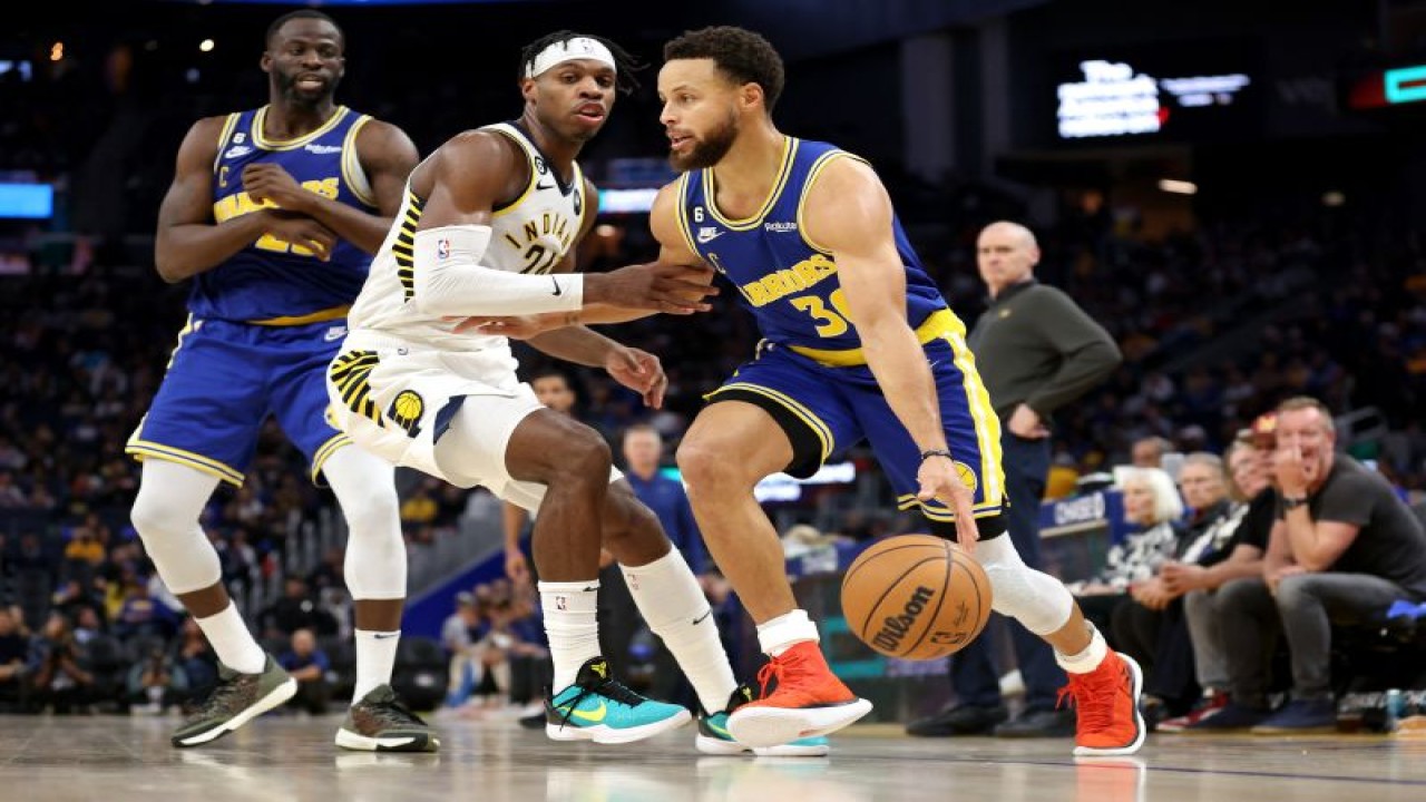 Pebasket Golden State Warriors Stephen Curry (kanan) mencoba melewati hadangan pebasket Indiana Pacers Buddy Hield (tengah) saat pertandingan NBA kedua tim Chase Center, San Francisco, California, Senin (5/12/2022) (Getty Images via AFP/EZRA SHAW)