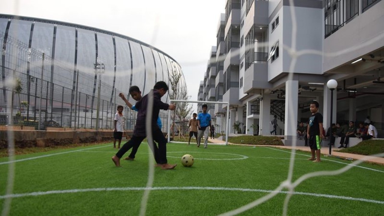 Anak-anak bermain bola di lapangan mini Kampung Susun Bayam, Tanjung Priok, Jakarta, Rabu (12/10/2022). Kampung Susun Bayam yang terdiri atas tiga menara yang memiliki 135 unit, tiga unit khusus disabilitas, fasilitas ruang terbuka dan lapangan sepak bola mini tersebut resmi digunakan sebagai hunian warga terdampak penggusuran akibat pembangunan Jakarta International Stadium (JIS). ANTARA FOTO/Indrianto Eko Suwarso/rwa.