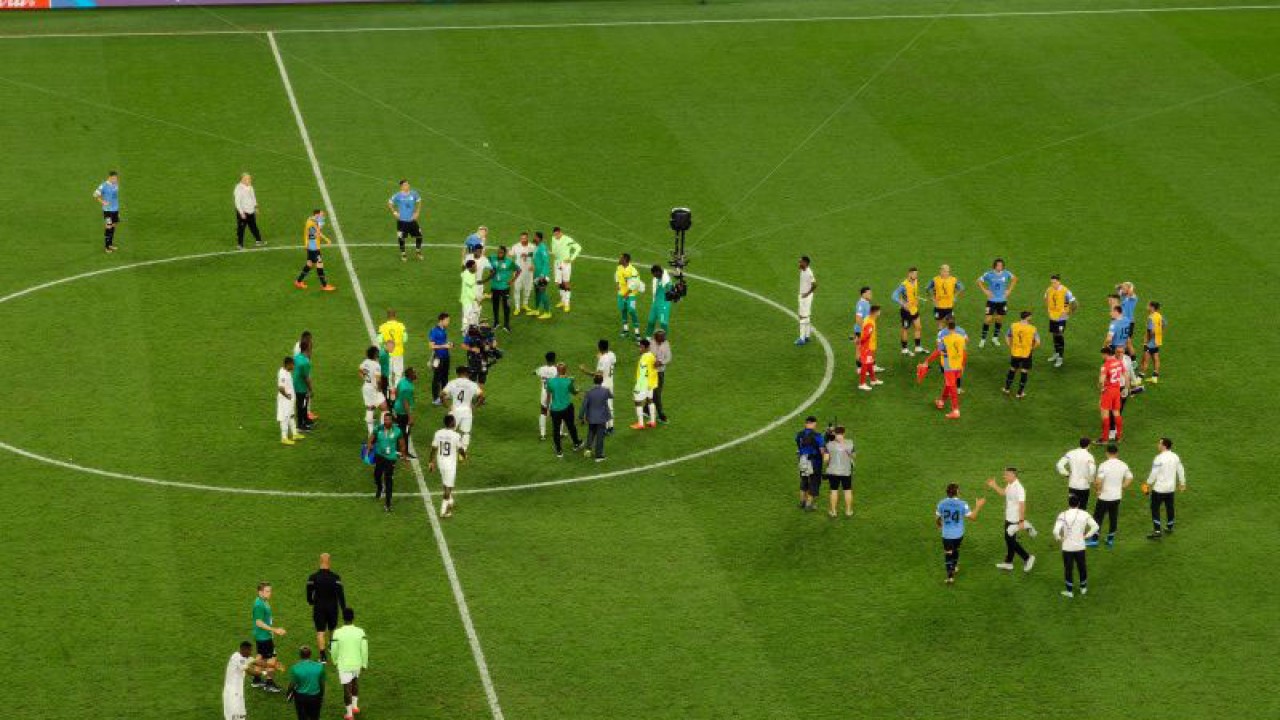 Para pemain tim nasional Ghana (kiri) dan Uruguay berkumlul di tengah lapangan Stadion Al Janoub, Al Wakra, Qatar, Jumat (2/2/2022) (ANTARA/Gilang Galiartha)