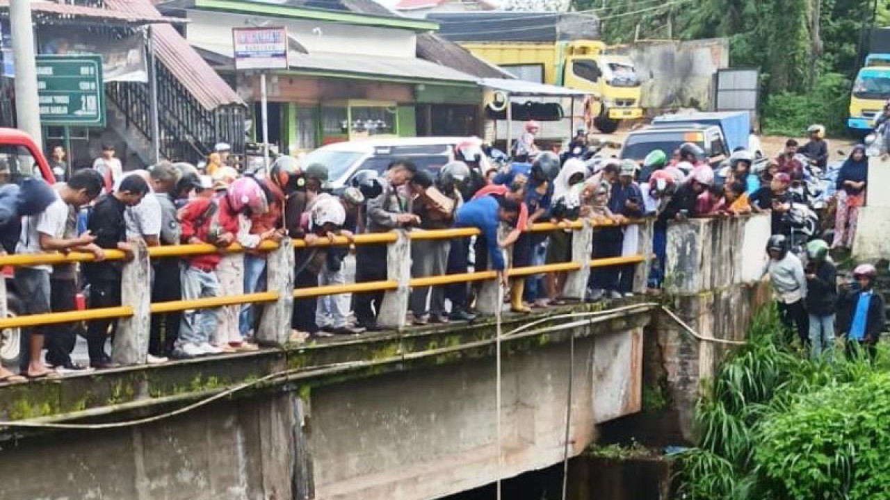 Petugas kepolisian dan warga melakukan evakuasi terhadap seorang yang diduga nekat mencoba bunuh diri di Jembatan Sungai Tanang. (Antara/HO-Dokumen Pribadi)