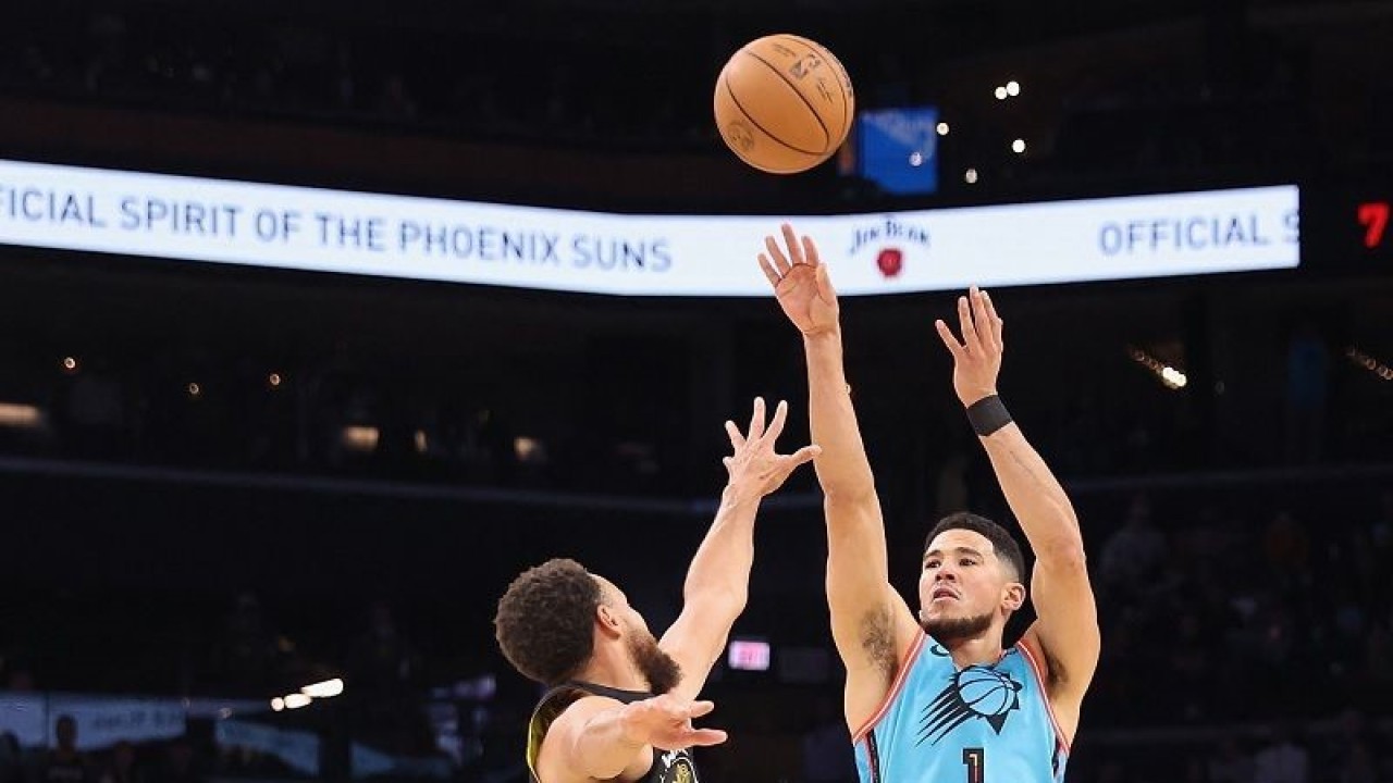 Arsip - Bintang Phoenix Suns Devin Booker (kanan) melepaskan tripoin di hadapan bintang Golden State Warriors Stephen Curry dalam lanjutan NBA di Footprint Center, Arizona, Amerika Serikat, Rabu (16/11/2022) waktu setempat. (ANTARA/AFP/GETTY IMAGES/Christian Petersen)