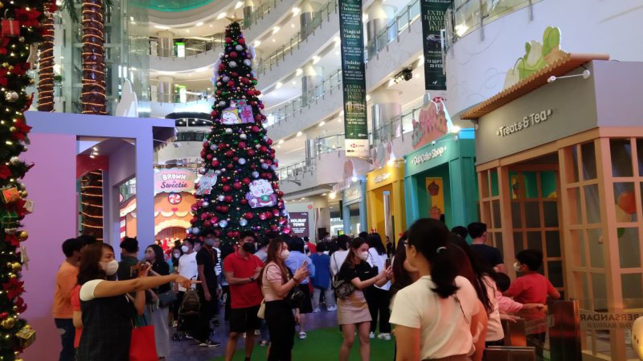 Warga berfoto dengan latar belakang pohon Natal di salah satu pusat perbelanjaan di Jakarta, Sabtu (17/12/2022). ANTARA/Dewa Ketut Sudiarta Wiguna
