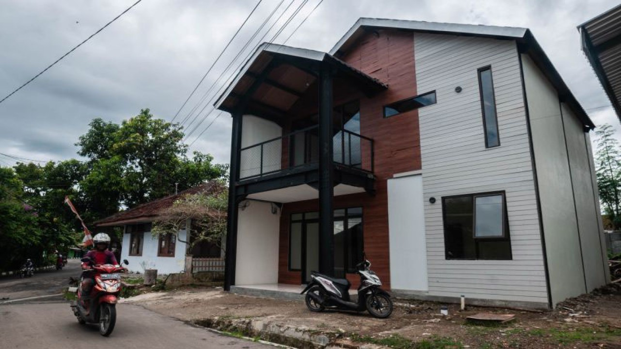 Warga melintas di depan rumah tahan gempa di Rangkasbitung, Lebak, Banten, Jumat (21/1/2022). Prototipe rumah tahan gempa yang dibangun oleh Badan Riset dan Inovasi Nasional (BRIN) tersebut dapat menahan gempa berkekuatan magnitudo 8,0 SR dan akan dijadikan sarana edukasi kegempaan bagi masyarakat. ANTARA FOTO/Muhammad Bagus Khoirunas/nym