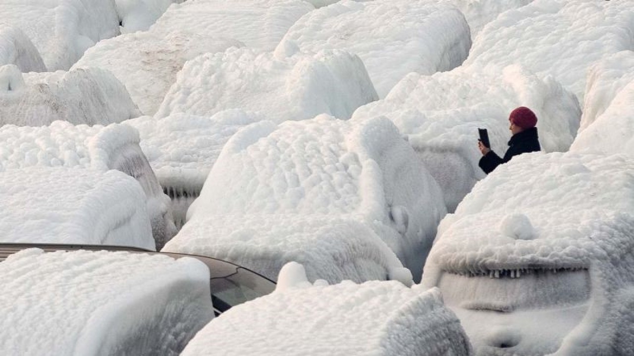 Ilustrasi--Seorang wanita memotret kendaraan berselimut salju diturunkan dari kapal kargo Sun Rio, yang terperangkap di cuaca buruk di Laut Jepang, di pelabuhan Vladivostok, Rusia, Rabu (29/12/2021). ANTARA FOTO/REUTERS/Tatiana Meel/AWW/djo