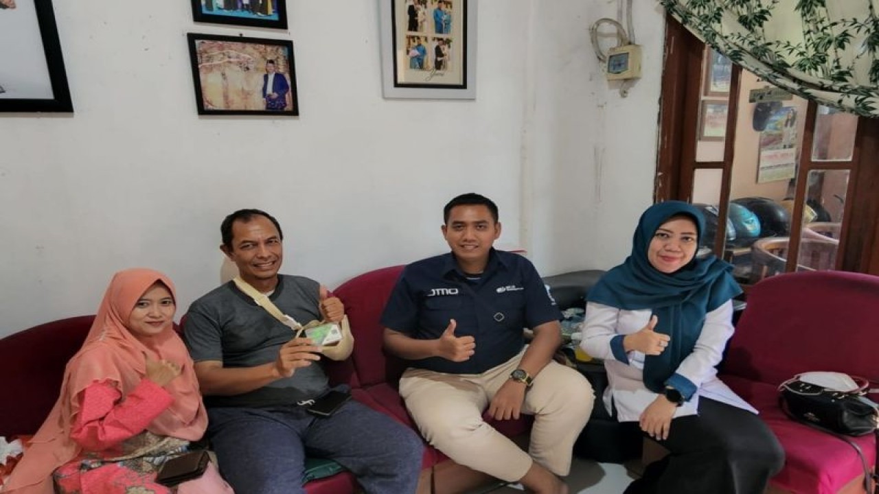 Sopir taksi Sri Budi Herawanto dan istrinya berfoto bersama pejabat BPJAMSOSTEK Kantor Pratama Bandara Soekarno Hatta di Tangerang, Banten. (HO BPJAMSOSTEK)