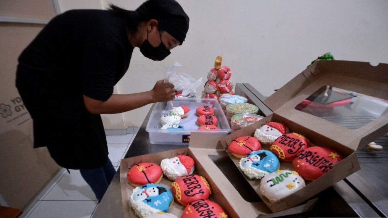 Karyawan menyelesaikan proses pembuatan donat bertema Natal di Kania Cake, Badung, Bali, Rabu (21/12/2022). Berbagai jenis kue dan roti seperti kue kering karakter, kue gulung dan donat yang diproduksi sebagai bingkisan Hari Raya Natal itu dijual dengan harga Rp50 ribu sampai Rp320 ribu per paket dan dipasarkan ke sejumlah daerah di wilayah Bali. ANTARA FOTO/Fikri Yusuf/YU (ANTARA FOTO/FIKRI YUSUF)