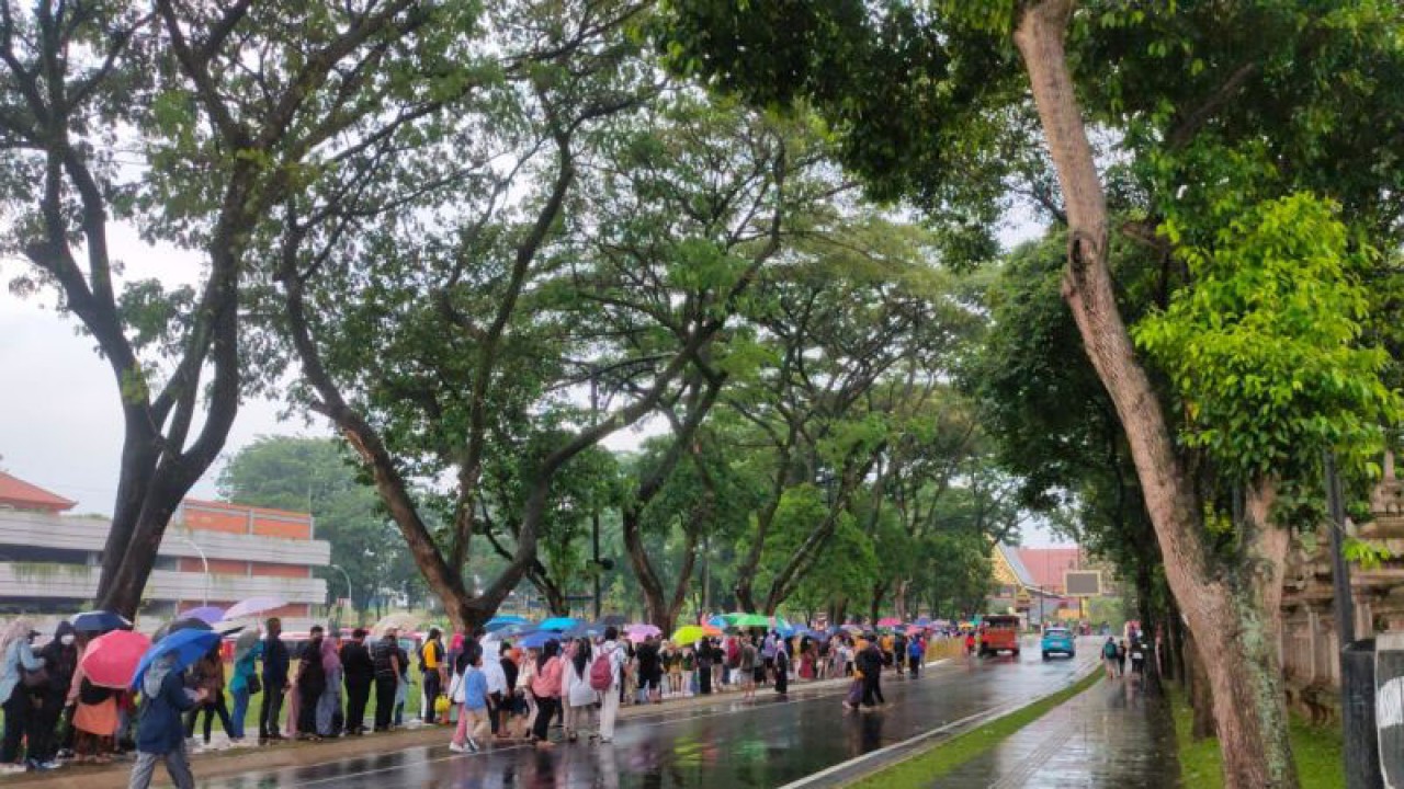 Hujan tak menyurutkan warga tetap mengantre masuk Taman Mini Indonesia Indah (TMII), Jakarta Timur, Sabtu (24/12/2022). (ANTARA/Laily Rahmawaty)