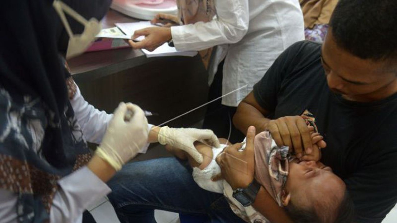 Seorang kepala rumah tangga (kanan) menggendong anaknya saat diberikan suntikan vaksin pada kegiatan bulan imunisasi anak di Desa Tibang, Banda Aceh, Aceh, Rabu (14/9/2022). (ANTARA FOTO/Ampelsa)