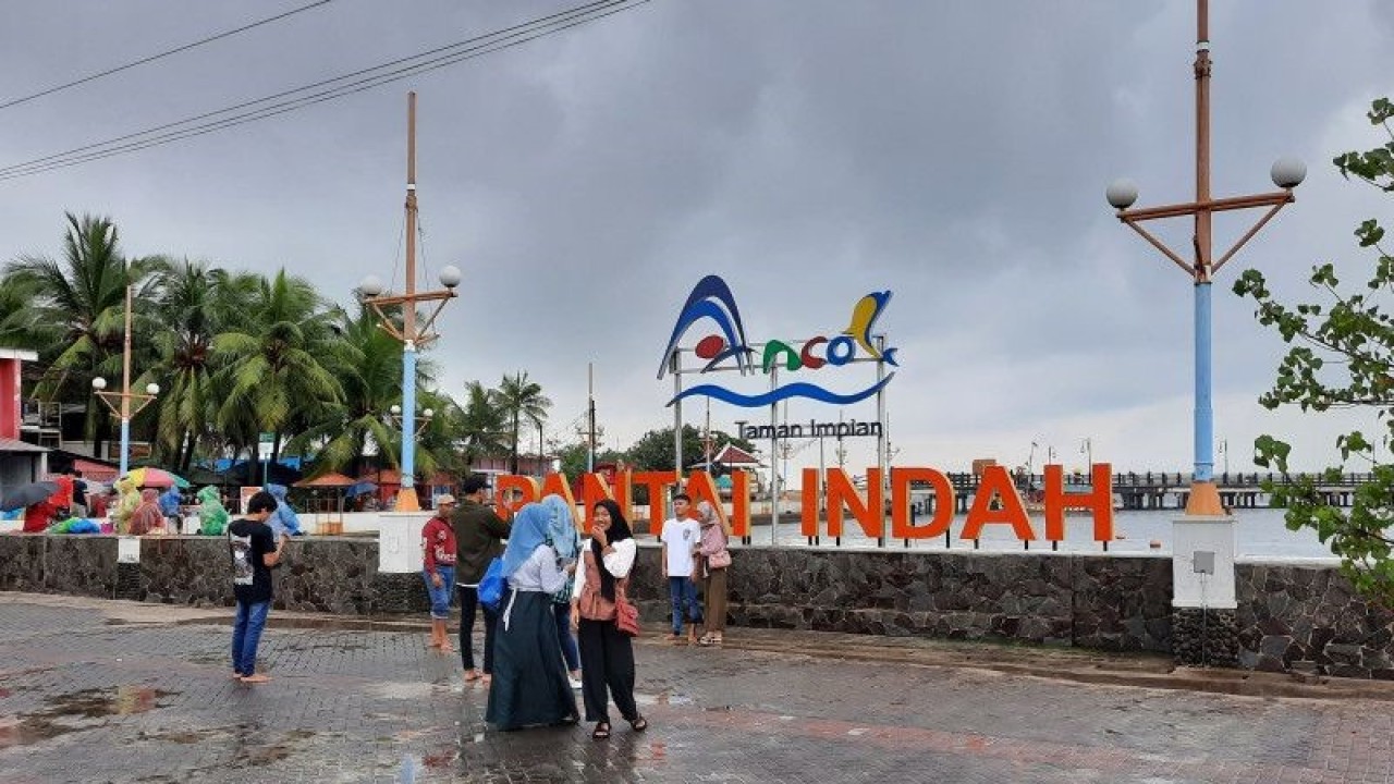 Sejumlah pengunjung berfoto di area pantai di kawasan wisata Ancol Taman Impian, Jakarta Utara pada Minggu (1/1/2023). (ANTARA/Lia Wanadriani Santosa)