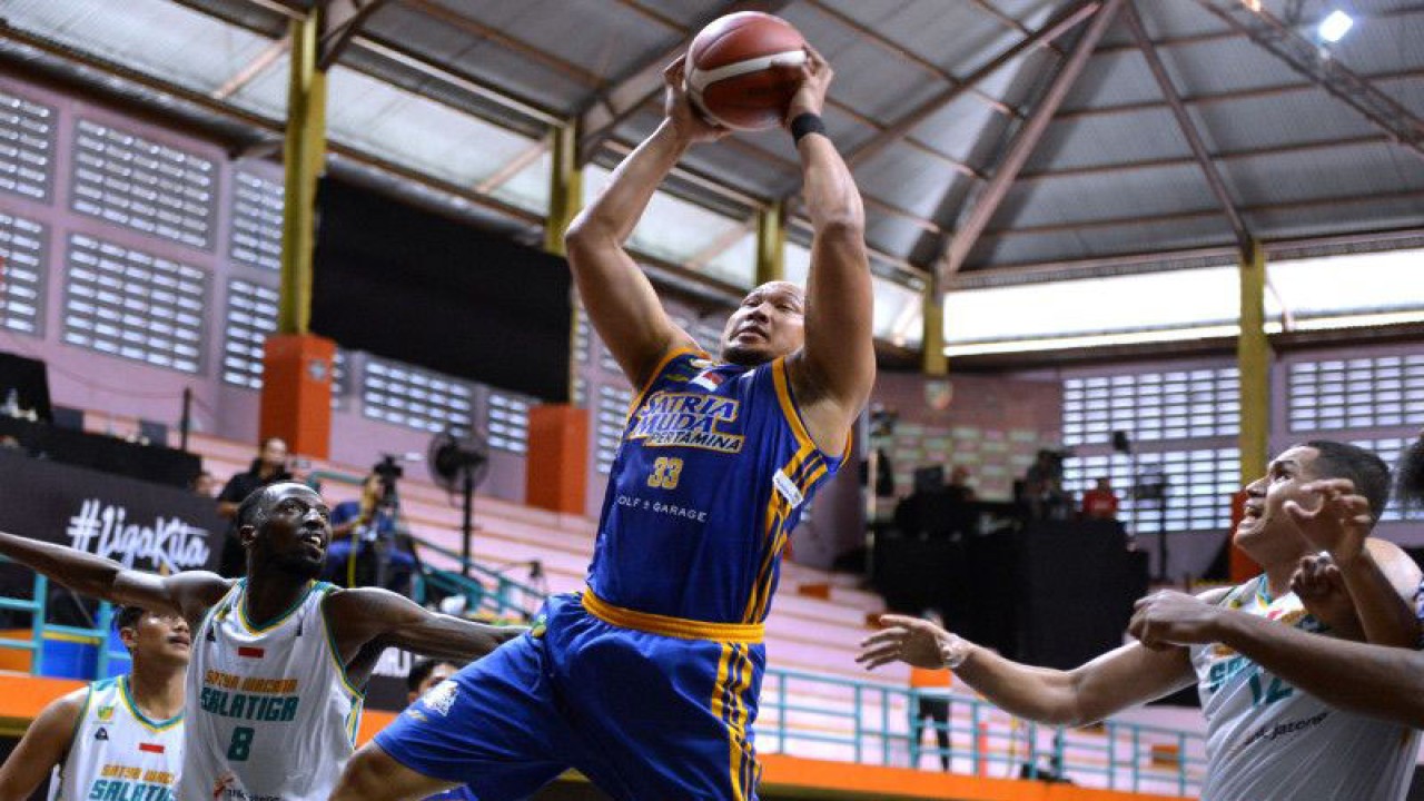 Pebasket Satria Muda Pertamina Jakarta Arki Dikania Wisnu (tengah) berusaha melewati hadangan pebasket Satya Wacana Salatiga Shemar Dearies Johnson (kiri) dan Henry Cornelis Lakay (kanan) saat pertandingan Indonesian Basketball League (IBL) 2023 di GOR Merpati, Denpasar, Bali, Sabtu (21/1/2023). ANTARA FOTO/Fikri Yusuf/YU